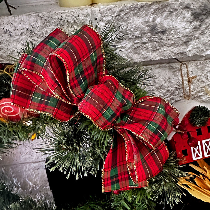 Red plaid bow on a Christmas tree with a stone fireplace background