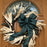 A rustic holiday wreath with dried palm fronds, evergreen branches, and white faux snow, decorated with a large dark green plaid bow, hanging on a brown wooden front door.