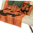 An orange and black jack-o'-lantern themed throw blanket and matching pillow set draped over a white tufted futon sofa.
